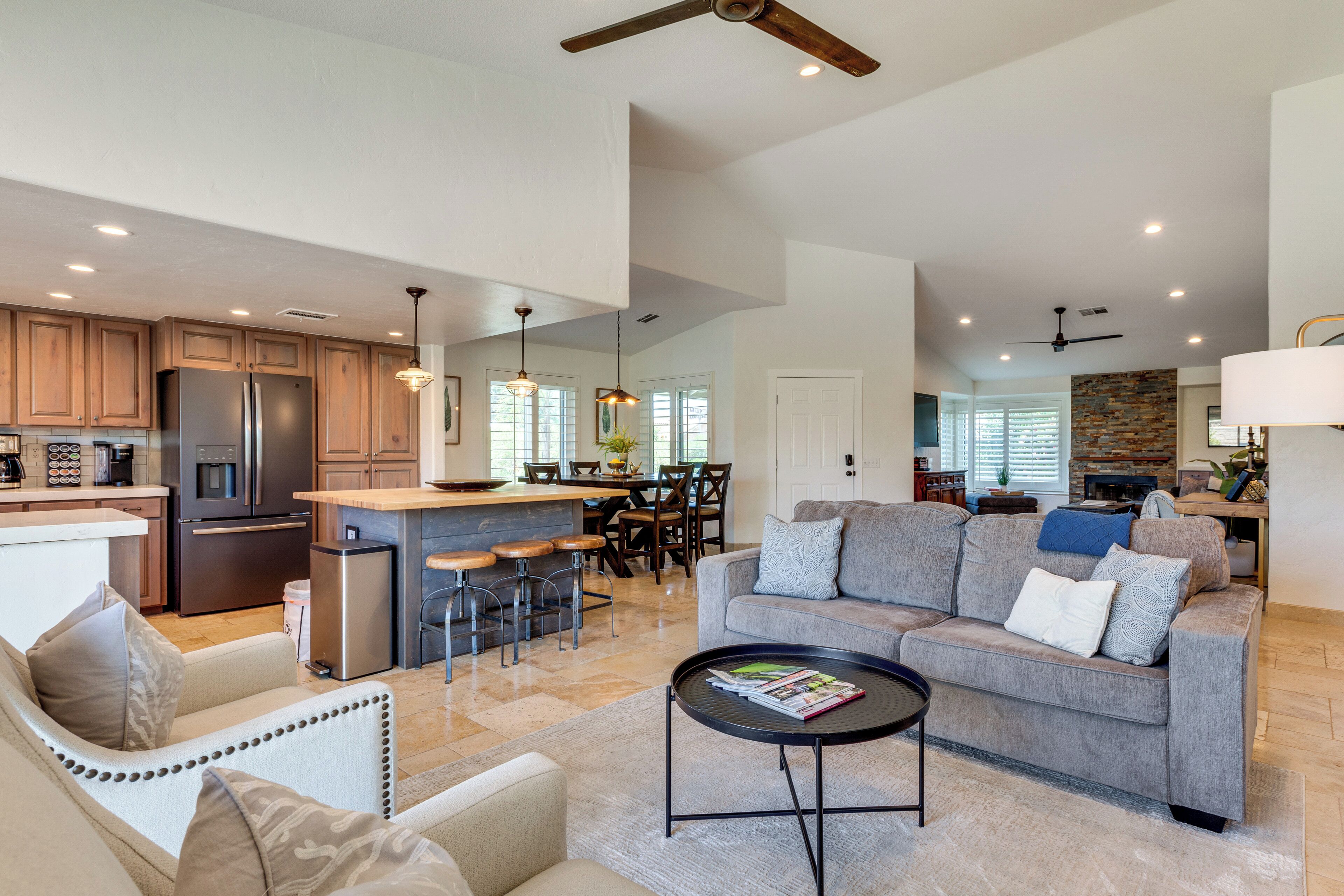 A modern kitchen with a central island, bar stools, and a dining area with a table and chairs.
