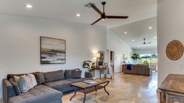 A spacious living room with a grey sectional sofa, a coffee table, and a ceiling fan. - Enjoy Luxury By Tennis/coachella/stagecoach (Indian Wells)