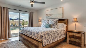 A bedroom with a bed, two bedside tables, a ceiling fan, and a view of a pool. - Enjoy Luxury By Tennis/coachella/stagecoach (Indian Wells)