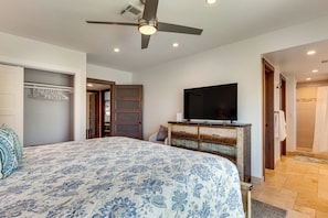 Ein Schlafzimmer mit Bett, Fernseher, Deckenventilator und einem Badezimmer mit Dusche.