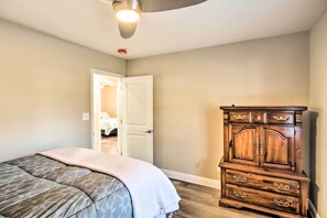 Um quarto com uma cama, cômoda de madeira e uma porta que dá para outro espaço.
