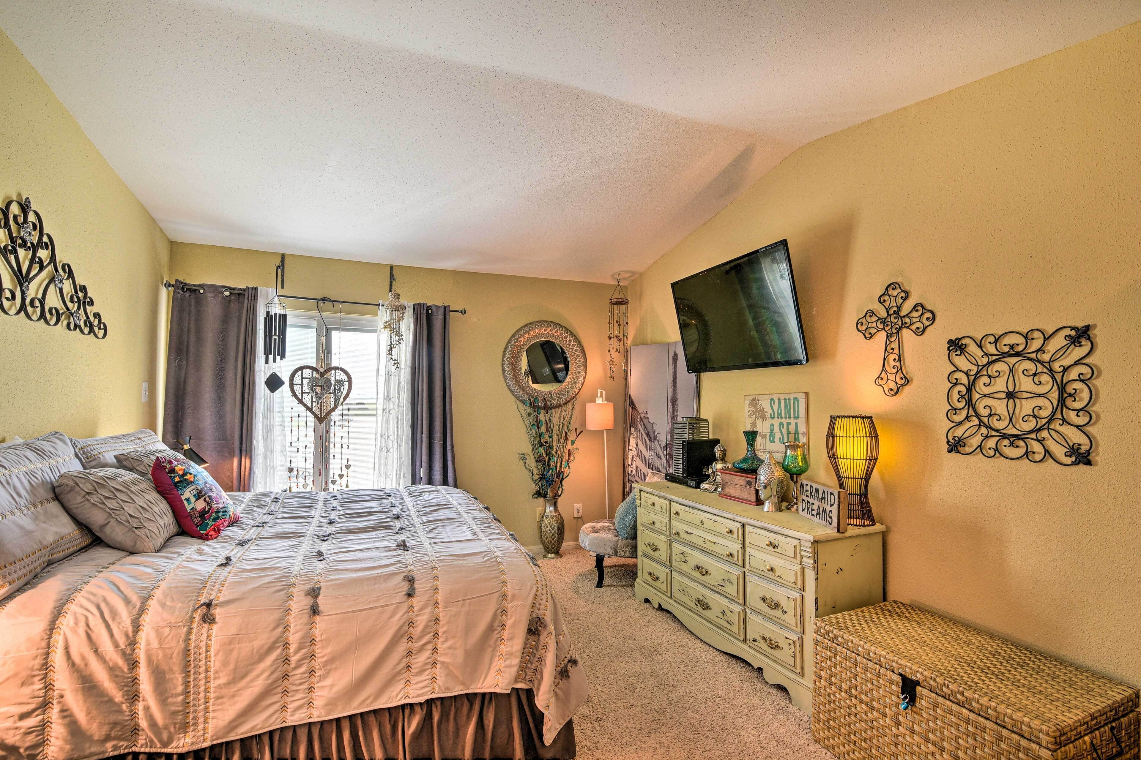A bedroom with a bed, dresser, and a television on the wall.