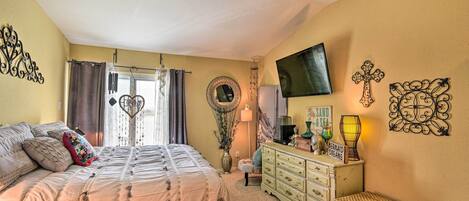 A bedroom with a bed, dresser, and a television on the wall.