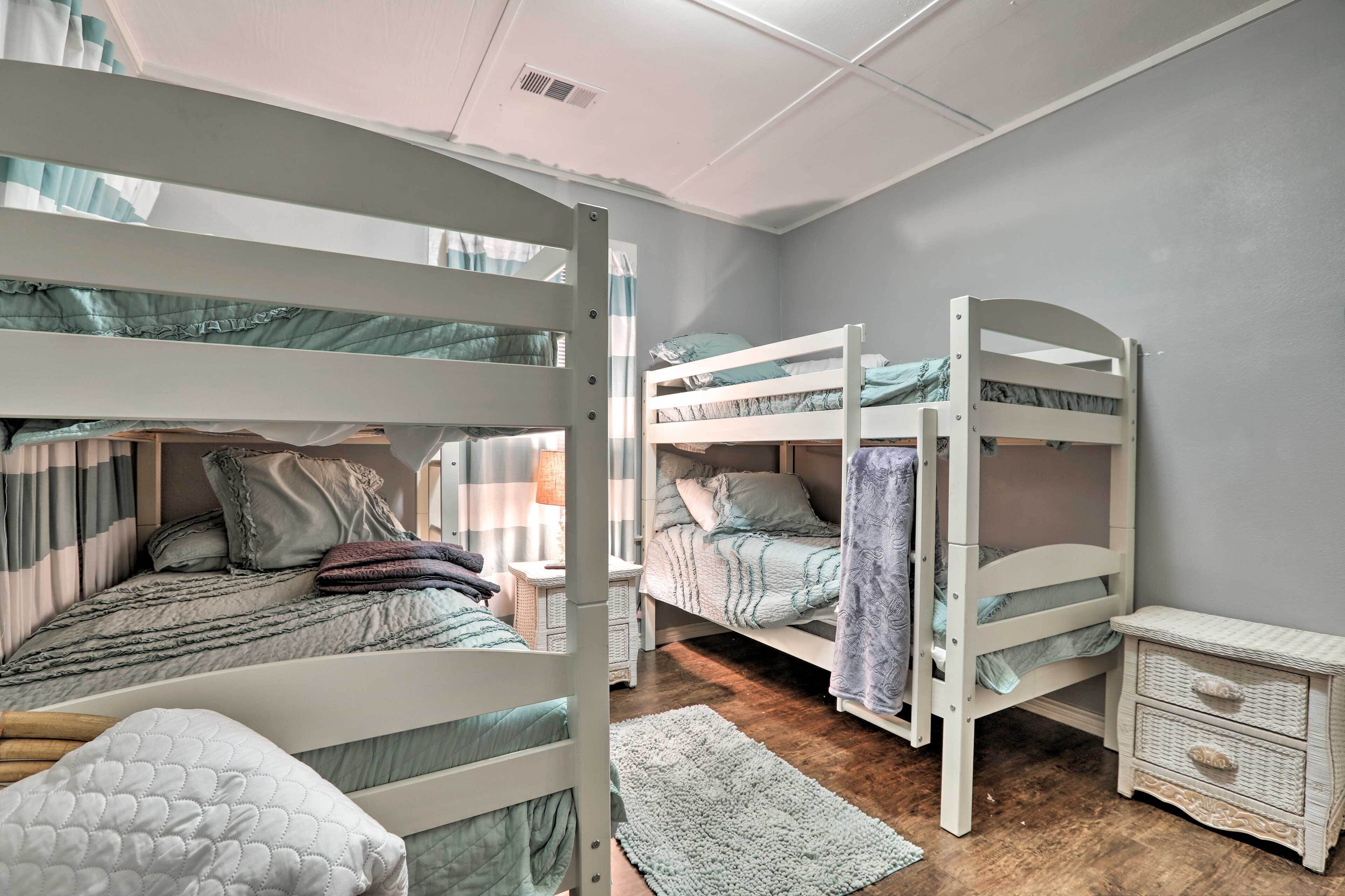 A children's bunk bed room with a white nightstand and a small white chest of drawers.