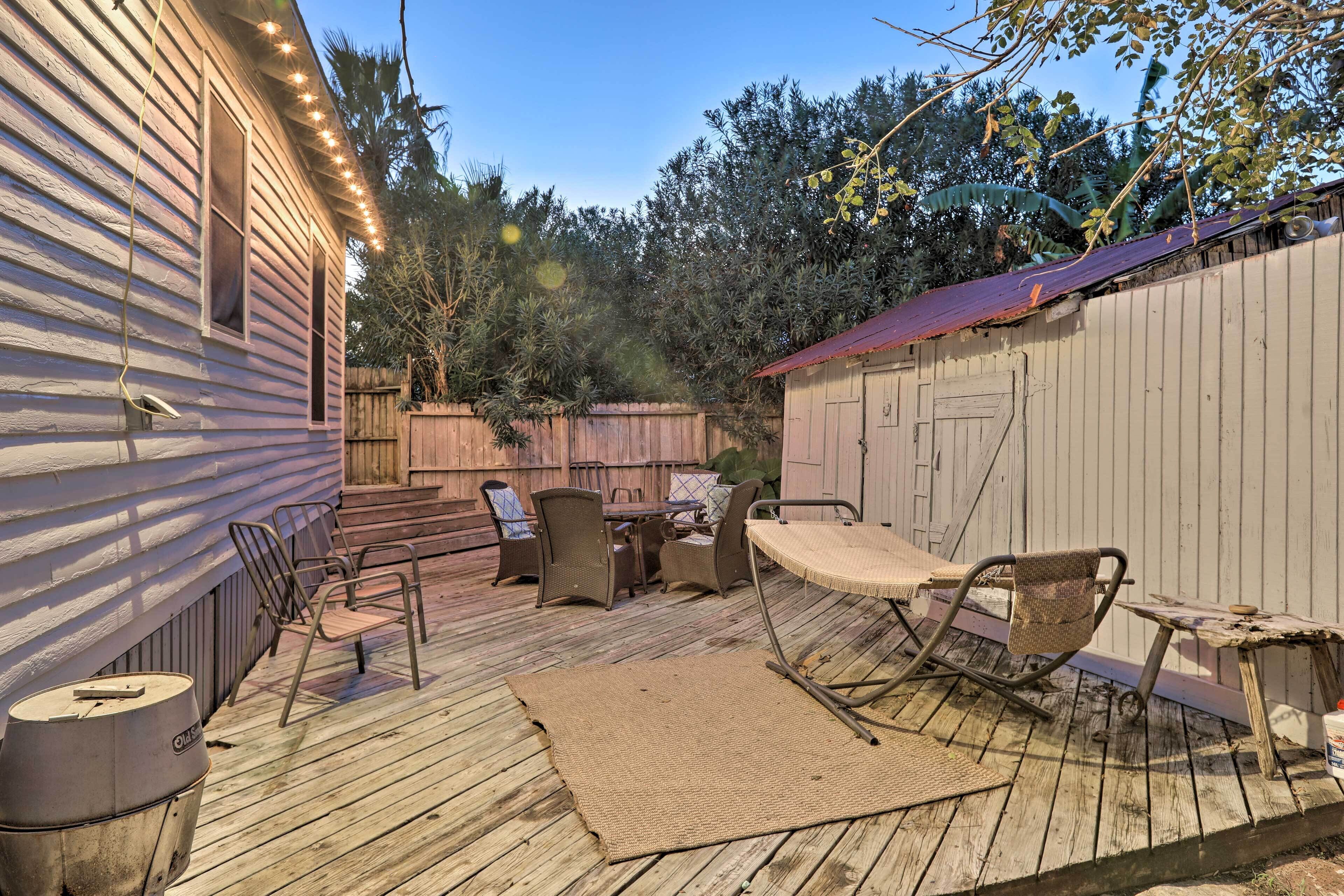 A wooden deck with outdoor furniture, a pergola with string lights, and a wooden fence.