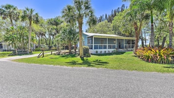 A single-story building with a porch, surrounded by palm trees and a well-maintained lawn.