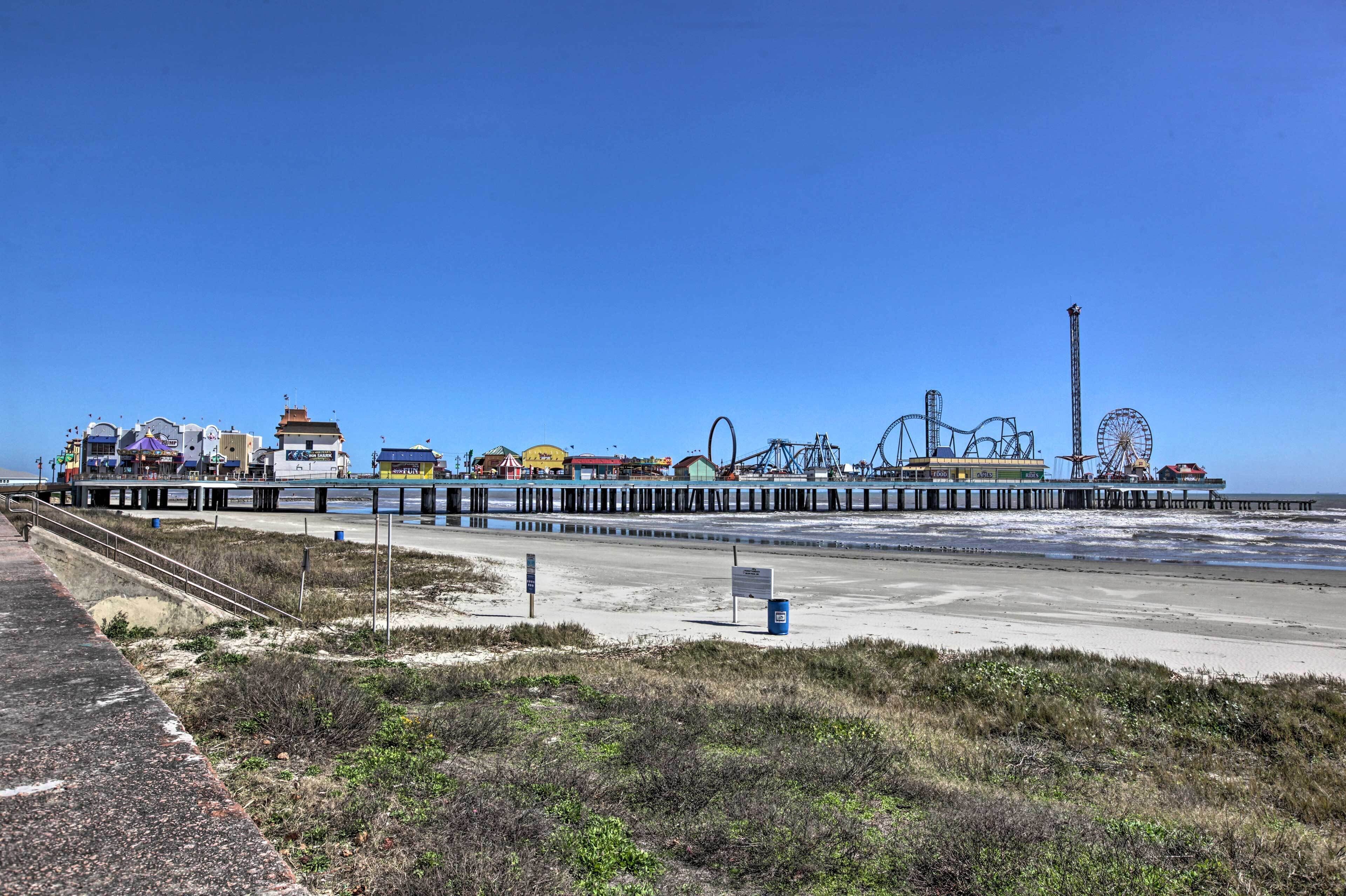 A pier with amusement rides and a beach area.