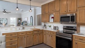 A modern kitchen with wooden cabinets, stainless steel appliances, and a large island with a sink.