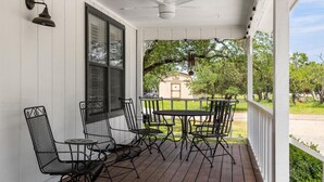 A covered porch with a table and chairs, a ceiling fan, and a view of a house in the background.