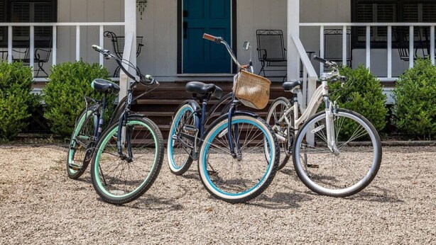 A porch with three bicycles, a blue door, and a number '297' above the door.