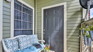A porch with a blue and white sofa, a small table with drinks, and a dark door. - < 1 Mi to Stewart Beach: Gem in East End Galveston (Galveston)
