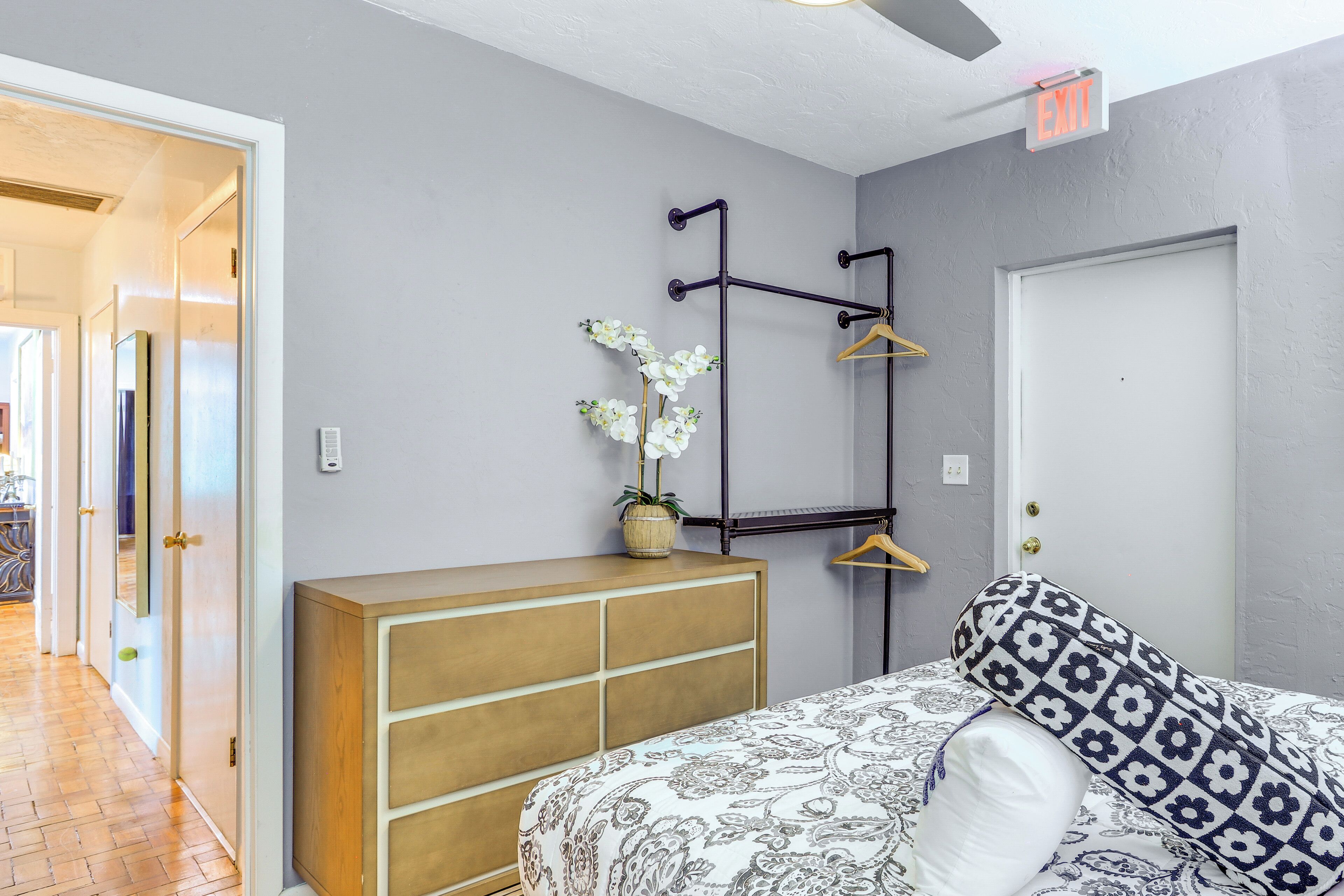 A bedroom with a bed, a dresser, a hanging light fixture, and a door.
