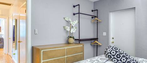 A bedroom with a bed, a dresser, a hanging light fixture, and a door.