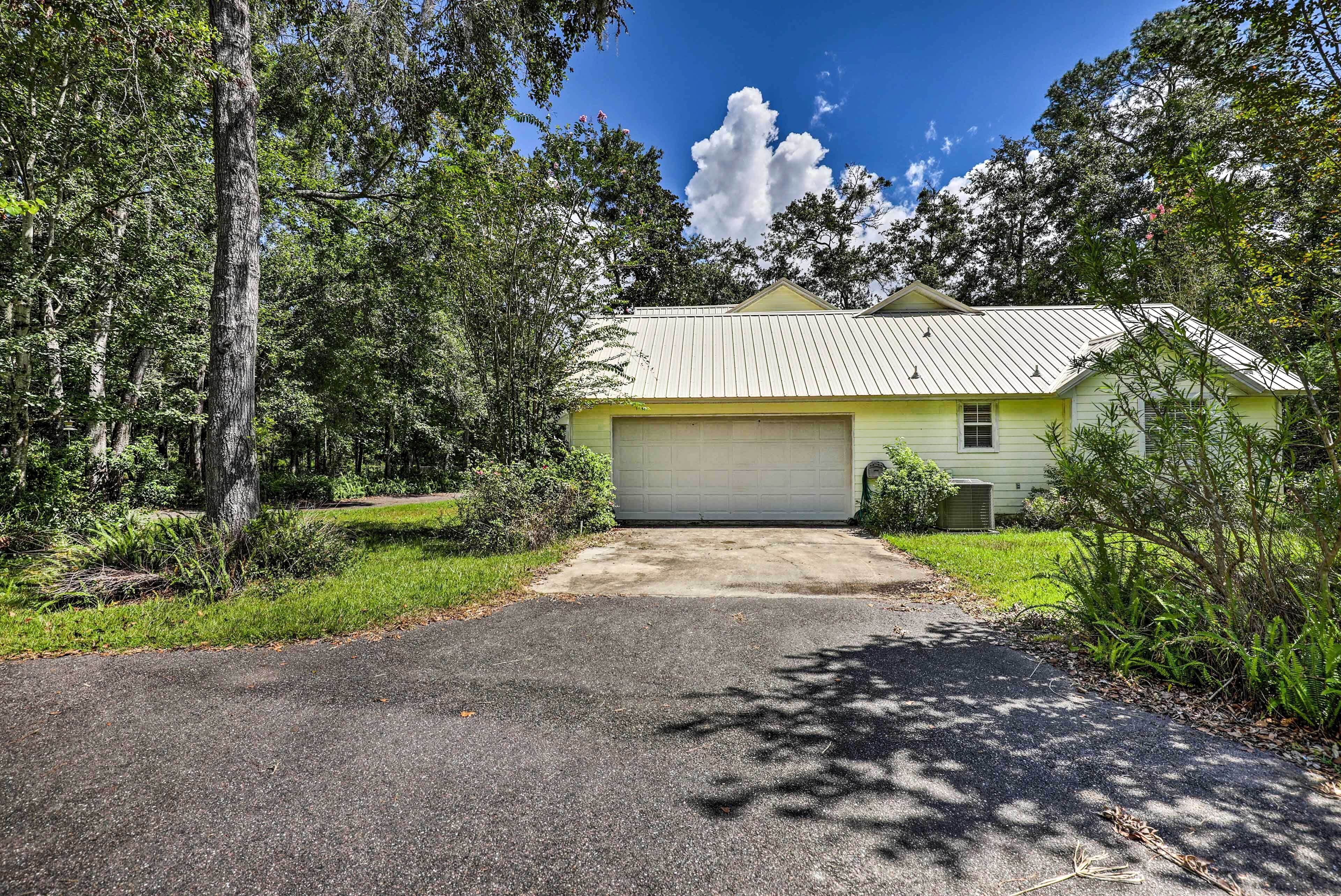 A single-story house with a garage, surrounded by trees and a clear sky.