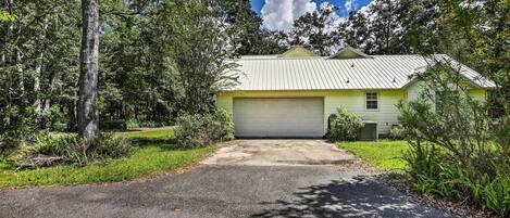 A single-story house with a garage, surrounded by trees and a clear sky.