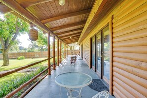 A covered porch with wooden beams, a glass table, and chairs.