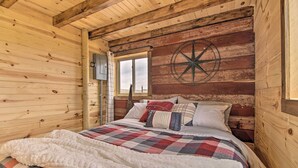 A wooden cabin bedroom with a bed, a compass wall decoration, and a window.