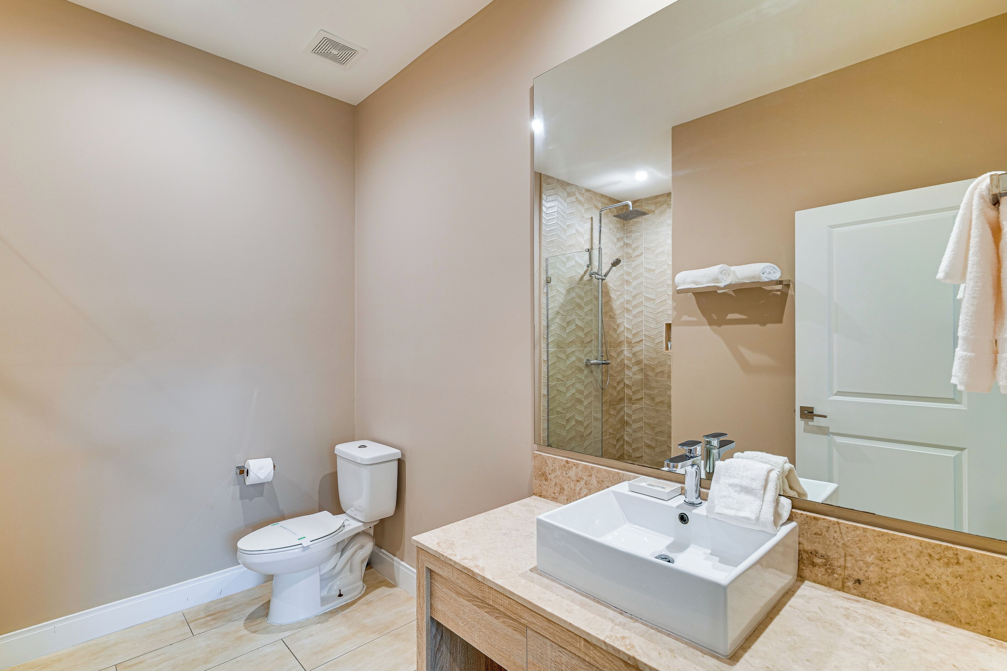 A modern bathroom with a toilet, sink, and shower area.