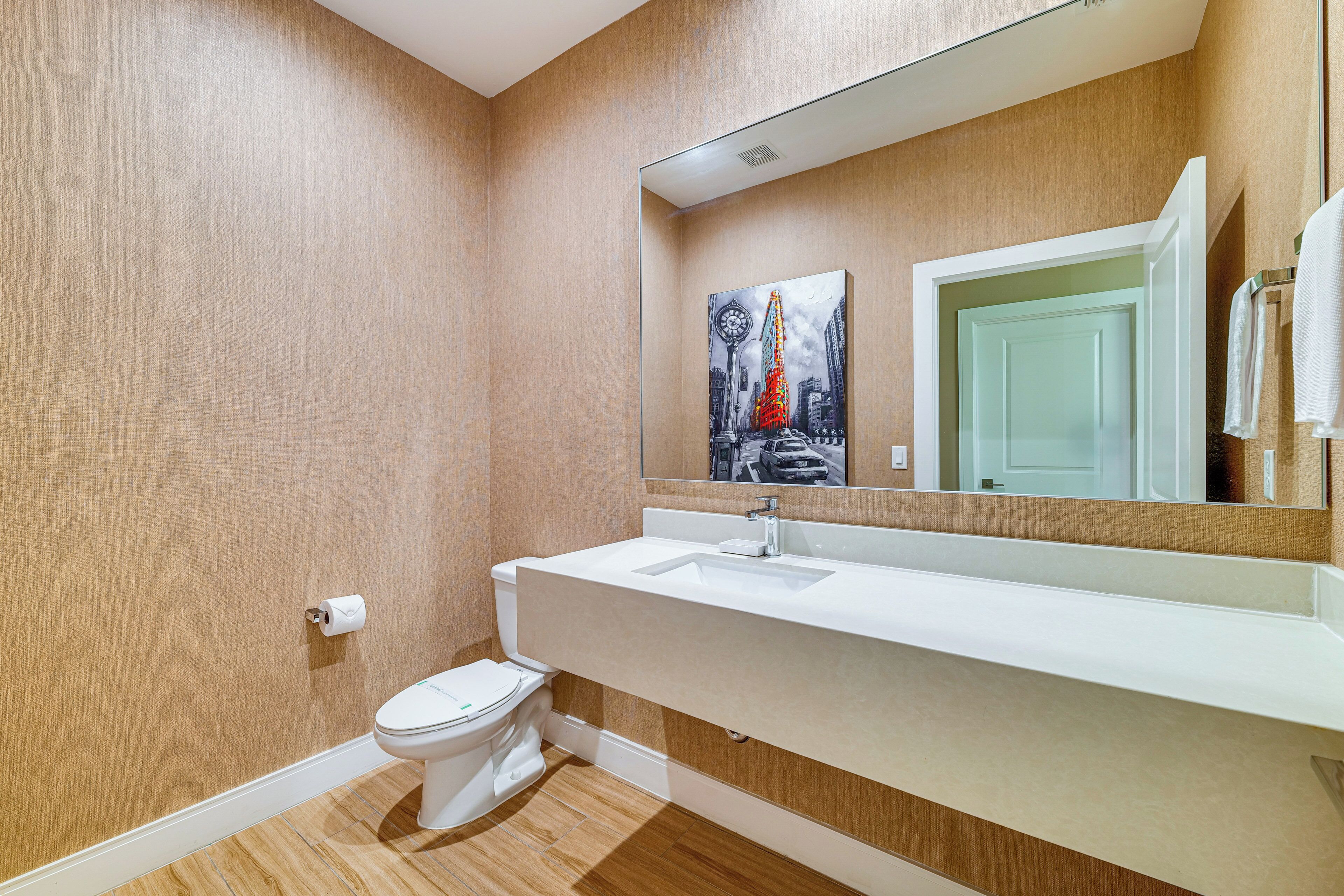 A bathroom with a toilet, sink, and mirror.