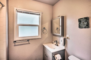 A bathroom with a window, a sink, a mirror, and a towel rack.