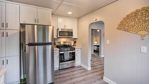 A modern kitchen with white cabinets, stainless steel appliances, and a wooden floor. - Cozy Elk Grove Home in the Heart of Old Town! (Elk Grove)