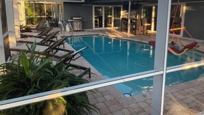 Un espace piscine avec des chaises longues et un coin salon abrité.