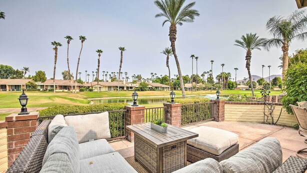 A patio with wicker furniture, a small table, and a view of a golf course and palm trees. - Palm Desert Escape w/ Patio & Shared Pool! (Palm Desert)
