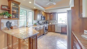 A spacious kitchen with wooden cabinets, a granite countertop, and a built-in oven. - Palm Desert Escape w/ Patio & Shared Pool! (Palm Desert)