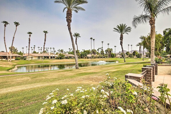 A golf course with a pond, palm trees, and well-maintained lawns. - Palm Desert Escape w/ Patio & Shared Pool! (Palm Desert)