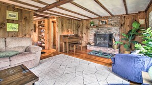 Una sala rústica con vigas de madera a la vista, una chimenea, un piano y un rincón de estar acogedor.