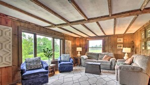 Una sala de estar acogedora con paredes y techo de madera, ventanas amplias y asientos cómodos.