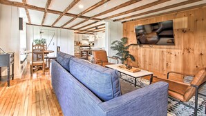 Una sala de estar moderna con techo de madera, un sofá grande azul, una mesa de centro y un televisor montado en una pared de madera.