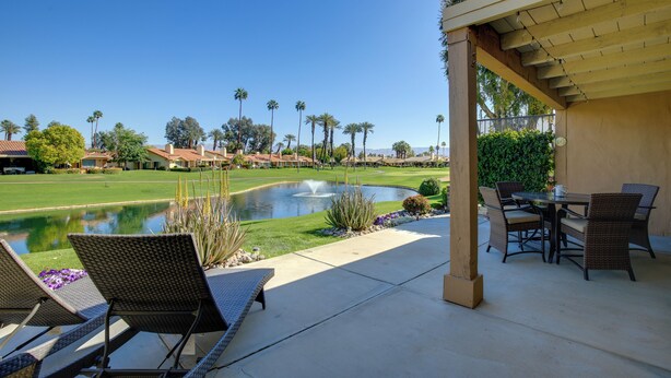 A patio with outdoor furniture, a pond, and a view of a golf course.