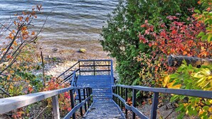 A wooden staircase leading to a dock by a lake, surrounded by autumn foliage. - Stunning South Hero Home on Lake Champlain w/ View (South Hero)