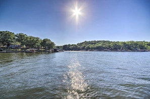A calm lake with a clear sky and trees on the opposite shore. - Sunrise Beach Home w/ Boat Dock on the Ozarks (Sunrise Beach)