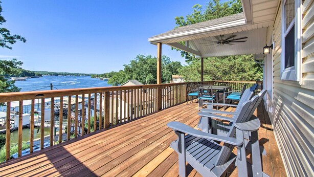 Une terrasse en bois, aménagée avec du mobilier d’extérieur, qui offre une vue sur une étendue d’eau et une zone de quai.