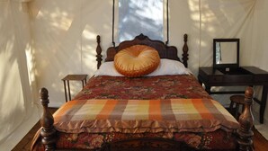A tented room with a bed, a desk, and a mirror.