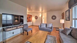 A modern living room with a flat-screen TV, grey sofas, a coffee table, and a TV stand with drawers. - Tulsa Rental Home - Walk to Philbrook Museum (Tulsa)