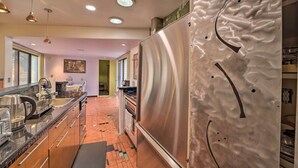 A modern kitchen with stainless steel appliances, a tiled backsplash, and pendant lighting. - Tulsa Rental Home - Walk to Philbrook Museum (Tulsa)