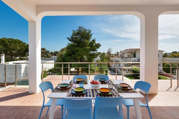 A dining area with a table set for four, overlooking a scenic view of trees and buildings.