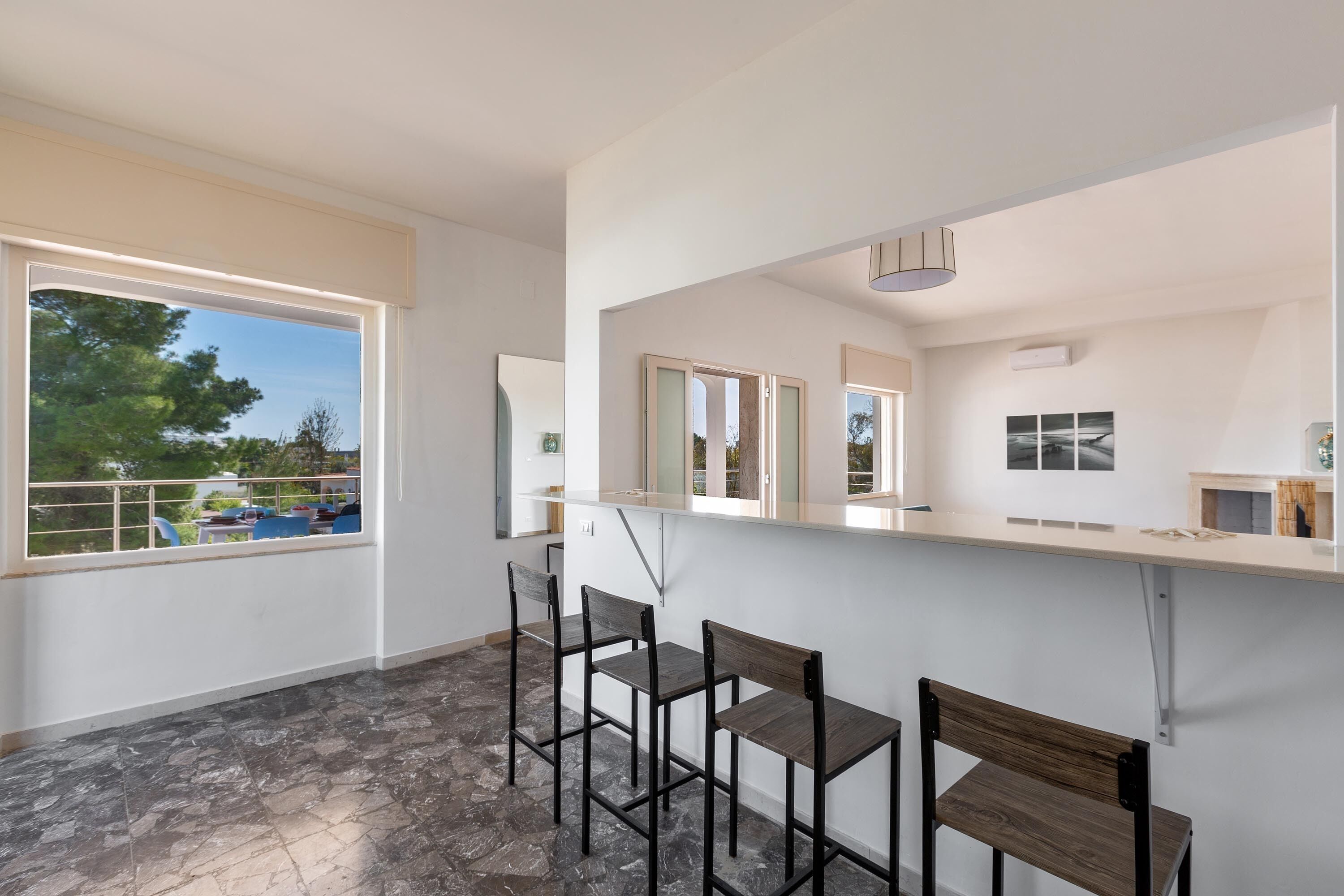 A modern kitchen with a bar area, large windows, and a view of the outdoors.