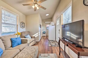 A living room with a sofa, ottoman, TV, and ceiling fan. - 1 Mi to Dtwn Rogers: Convenient Getaway w/ Patio (Rogers)