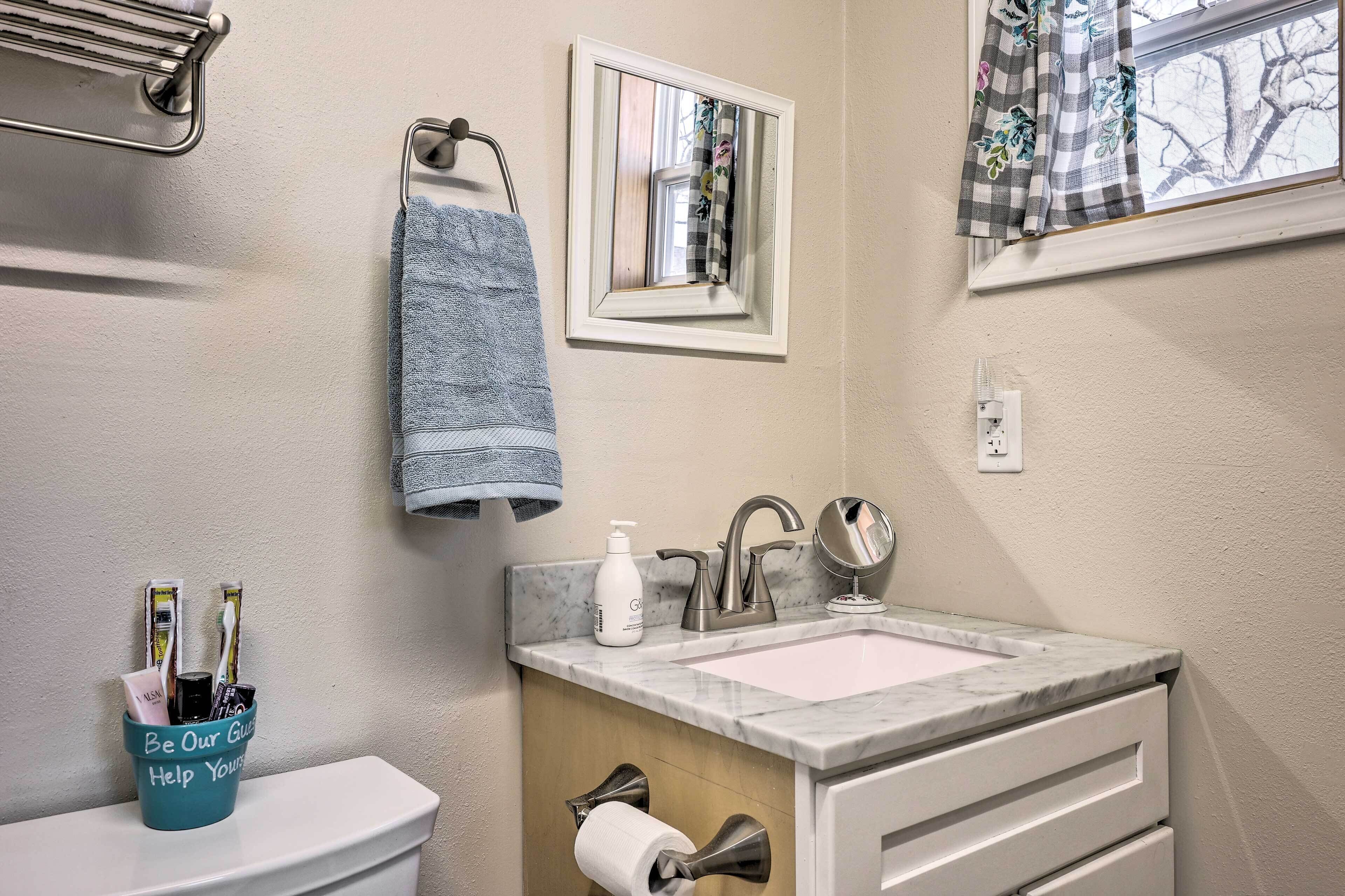 Une salle de bain avec un lavabo en marbre, un miroir, un porte-serviettes et un support à papier toilette.
