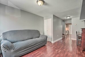 A spacious living room with a grey sofa, hardwood flooring, and a modern ceiling light fixture. - Modern Urban Escape in the Heart of Baltimore! (Baltimore)