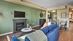 A living room with a fireplace, a sofa, a coffee table, and a dining area with chairs and a table. - Classic Fells Point Condo on Broadway Square! (Baltimore)