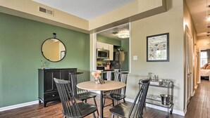 A dining area with a round table and chairs, a kitchen in the background, and a hallway leading to another room. - Classic Fells Point Condo on Broadway Square! (Baltimore)