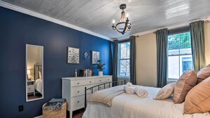 A bedroom with a bed, dresser, mirror, and a window with curtains. - Classic Fells Point Condo on Broadway Square! (Baltimore)