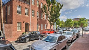 A row of parked cars along a brick building with multiple windows and a visible door. - Classic Fells Point Condo on Broadway Square! (Baltimore)