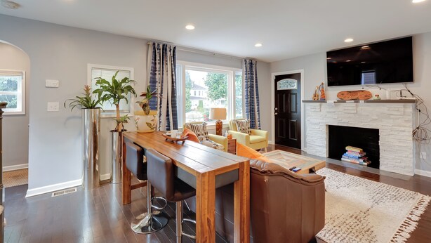 A modern living room with a fireplace, a dining area, and a large TV mounted on the wall. - Charming Baltimore Getaway - 5 Miles to Downtown! (Baltimore)