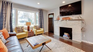 A living room with a sofa, armchairs, a coffee table, a fireplace, and a TV mounted on the wall. - Charming Baltimore Getaway - 5 Miles to Downtown! (Baltimore)